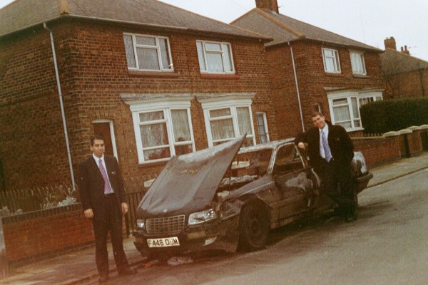 20 year old me, leaning against a burned out car on a council estate in the Northeast of England